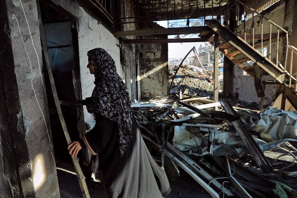 Una mujer de Gaza mira entre los escombros de su casa devastada en febrero de 2025. Foto: ONU Mujeres/Suad Al Nawajha